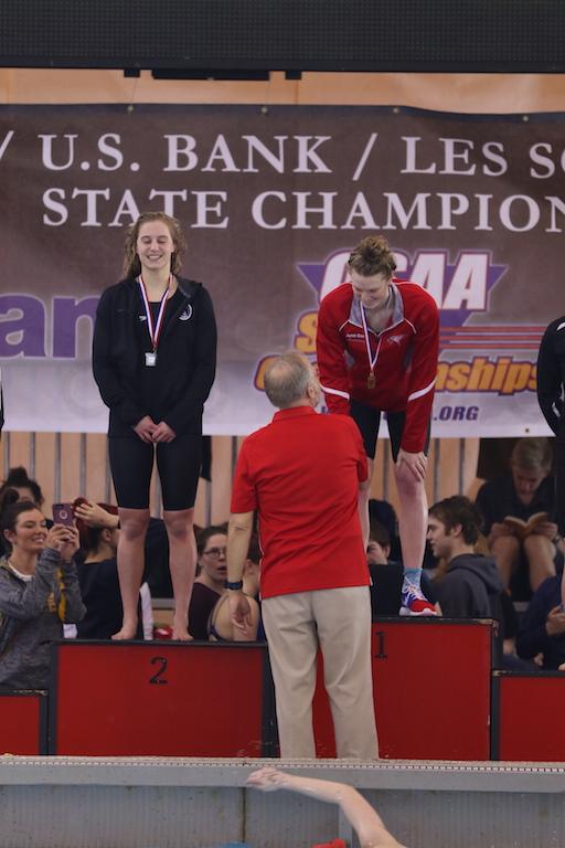Swim Coach Rod Lundgren presents four-time champion Jamie Stone with her 50m freestyle medal on Saturday.